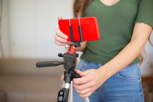 Free Female adjusting smartphone onto tripod for recording indoors. Stock Photo