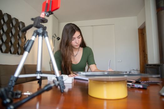 Woman filming a vlog in a home office setting, using a smartphone and tripod setup.