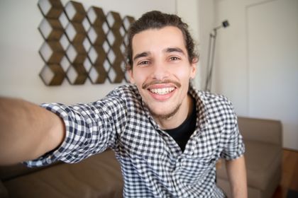 Happy caucasian man taking a selfie in a cozy indoor setting, with modern decor — photo by Kampus Production on Pexels