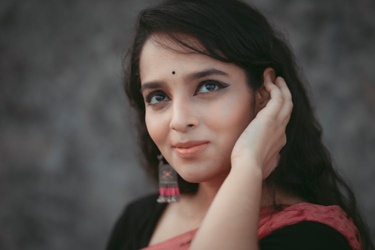 A Woman Wearing A Black Shirt Touching Her Ear