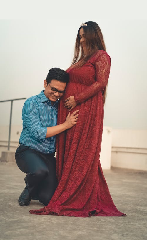 Free Man Kneeling in Front of a Pregnant Woman Stock Photo