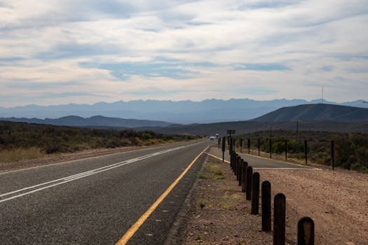 Scenic highway leading towards distant mountains under a cloudy sky.