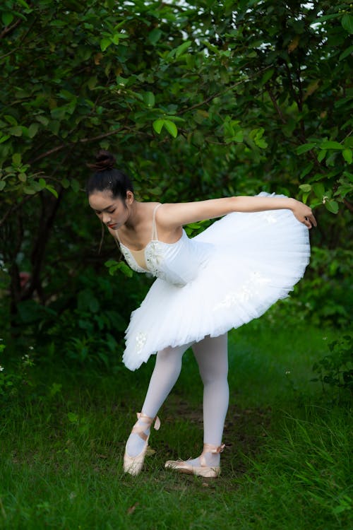 Ethnic woman in tutu dress and pointe shoes in park