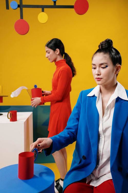 Free Two women in retro attire pose in a vibrant, colorful studio setting, embodying swinging sixties fashion. Stock Photo