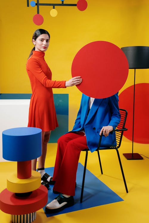 Woman in Orange Long Sleeve Dress Covering the Face of a Person 