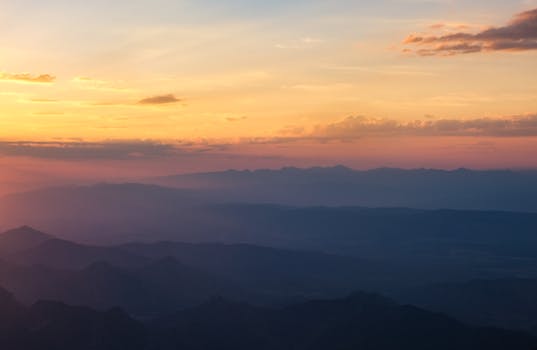 Stunning aerial view of a sunset over mountain ranges with dramatic clouds and vibrant colors.