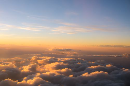 Free A breathtaking view of a golden sunrise casting warm hues over a sea of clouds. Stock Photo