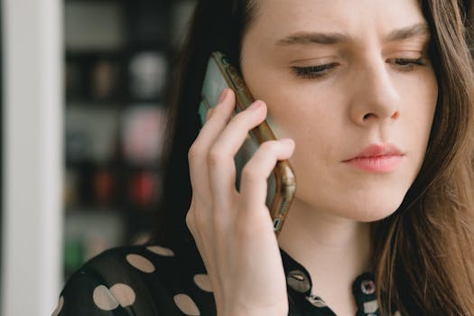 Close-up of a woman engaged in a phone conversation indoors, depicting a thoughtful expression.