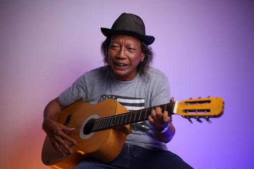 Mature Indian man playing guitar in studio