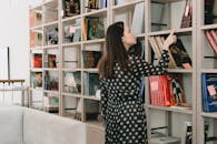 Young woman choosing book from bookshelf