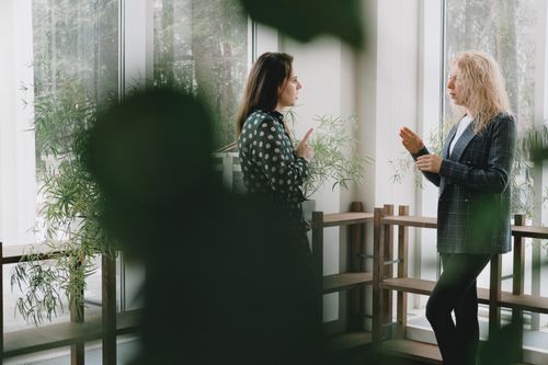 Free Side view of female workers in formal clothes discussing work issues and looking at each other Stock Photo