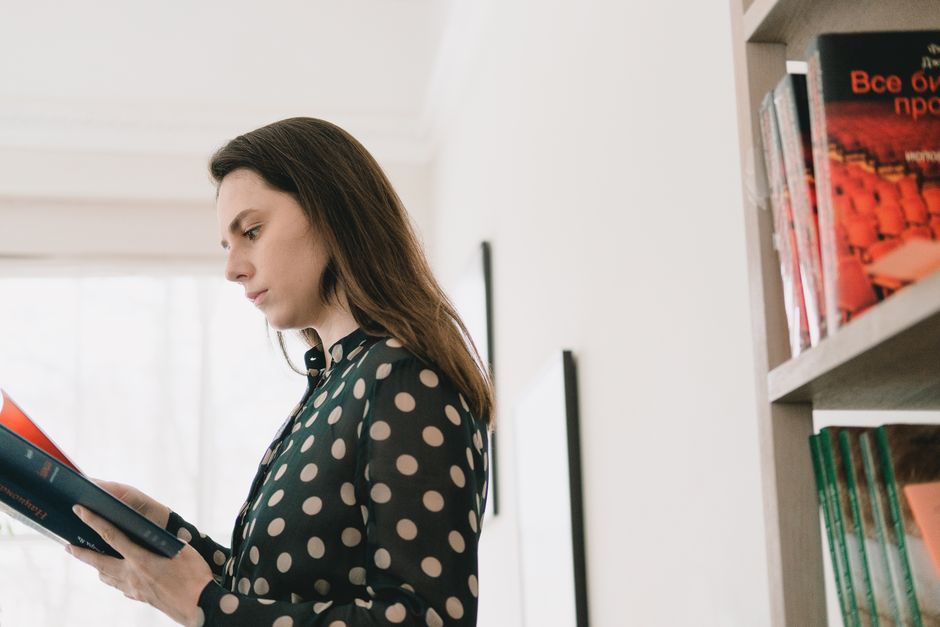 Profile of a woman intently reading a book in a serene library environment.