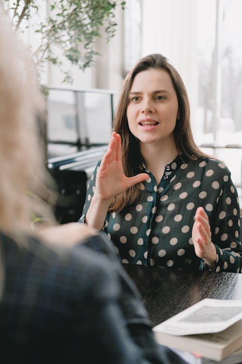 Free Young lady speaking with unrecognizable female teacher during lesson Stock Photo