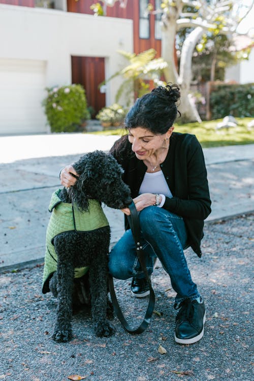 Woman Crouching Beside a Black Dog