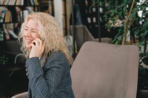 Free Cheerful woman smiling while talking on smartphone in cafe Stock Photo