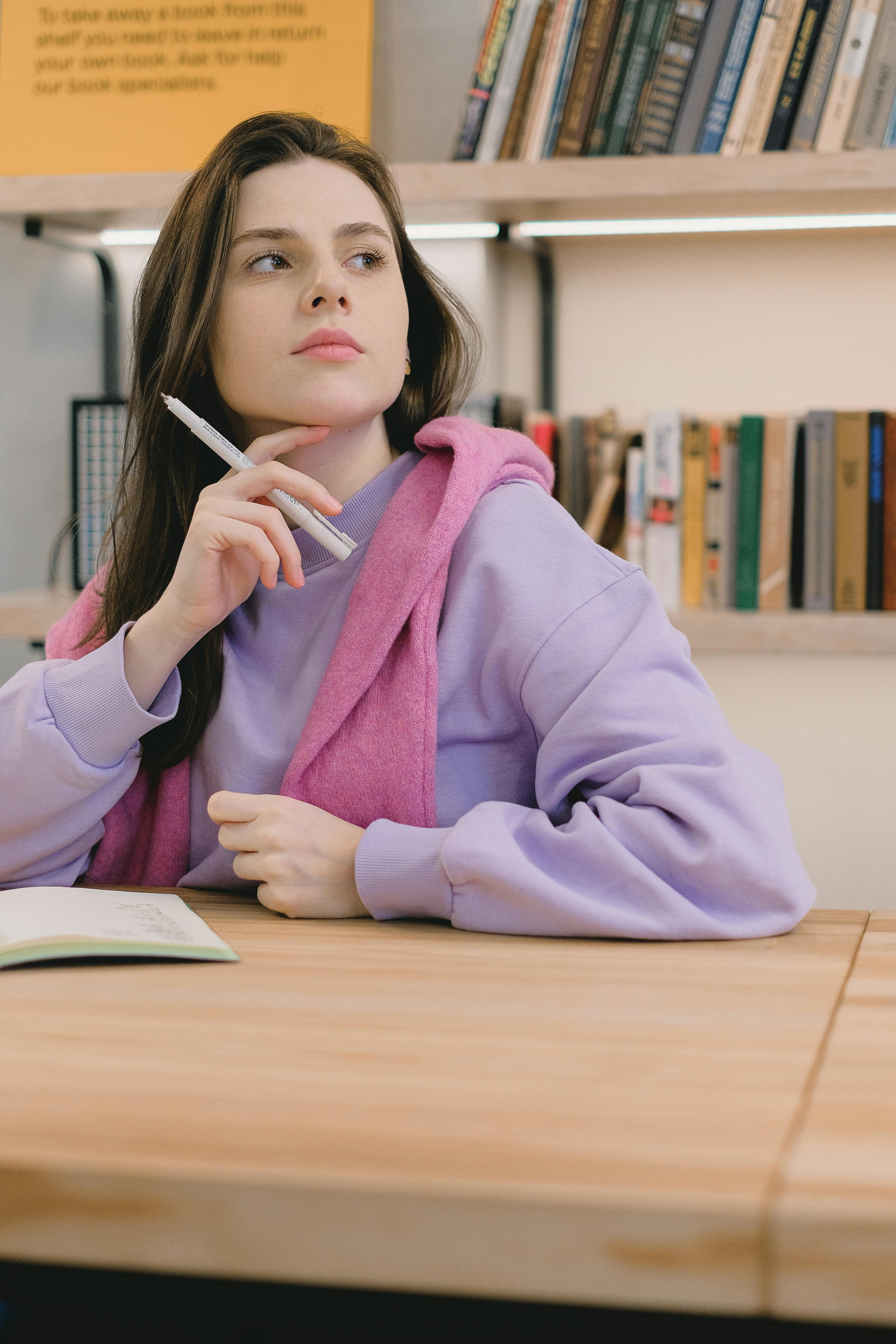 thoughtful young lady looking away while doing assignment in classroom