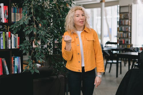 Woman talking to camera while standing in classroom during online lessons