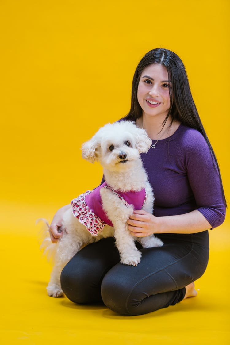 Woman In A Violet Shirt Kneeling With Her Dog