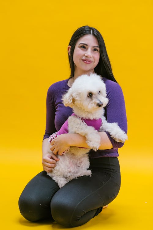 Smiling Woman Sitting while Carrying her Long Coated Small Dog