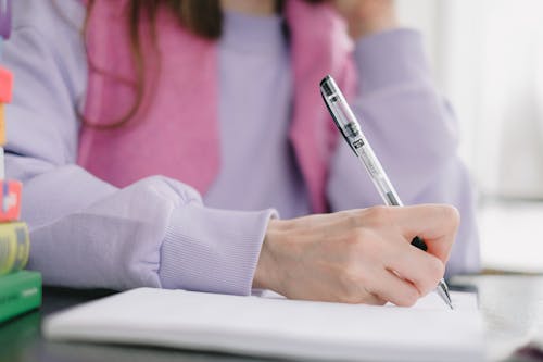 Crop woman writing in notebook