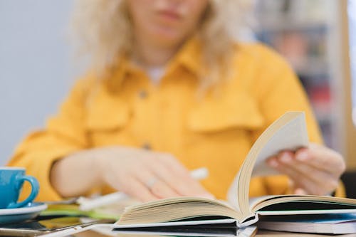 Free Crop student reading book at table Stock Photo