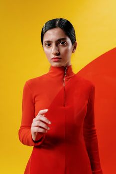 Striking studio portrait of a model in a red dress against a vibrant yellow background.