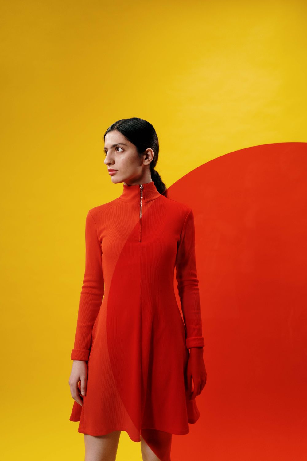 Portrait of a woman in a red dress on a bold colour backdrop