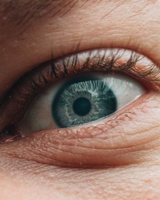 Closeup unrecognizable female with grey eye and long natural eyelashes looking at camera