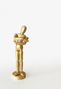Wooden artist mannequin painted gold standing on a minimalist white surface.