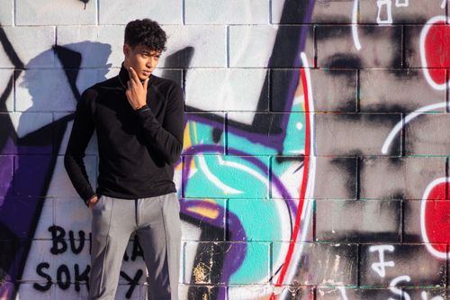 Free Young man posing stylishly against a vibrant graffiti wall in Valencia, Spain. Stock Photo