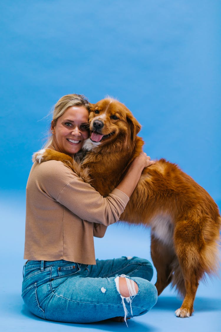 Woman Wearing A Sweater Sitting And Hugging A Dog