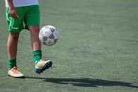 Person in Red Shorts and White Soccer Ball on Green Grass Field