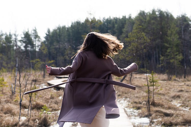 Woman In Gray Coat Running In Spring Forest