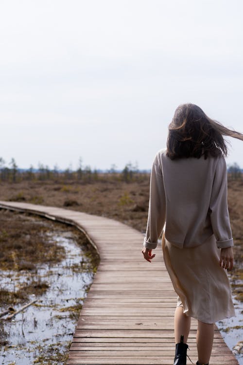 Carefree woman in casual stylish clothes walking on timber path