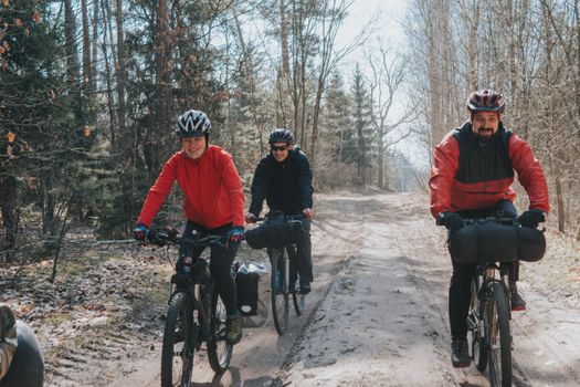 Three bikers ride through a forest path, enjoying outdoor adventure in Belarus.