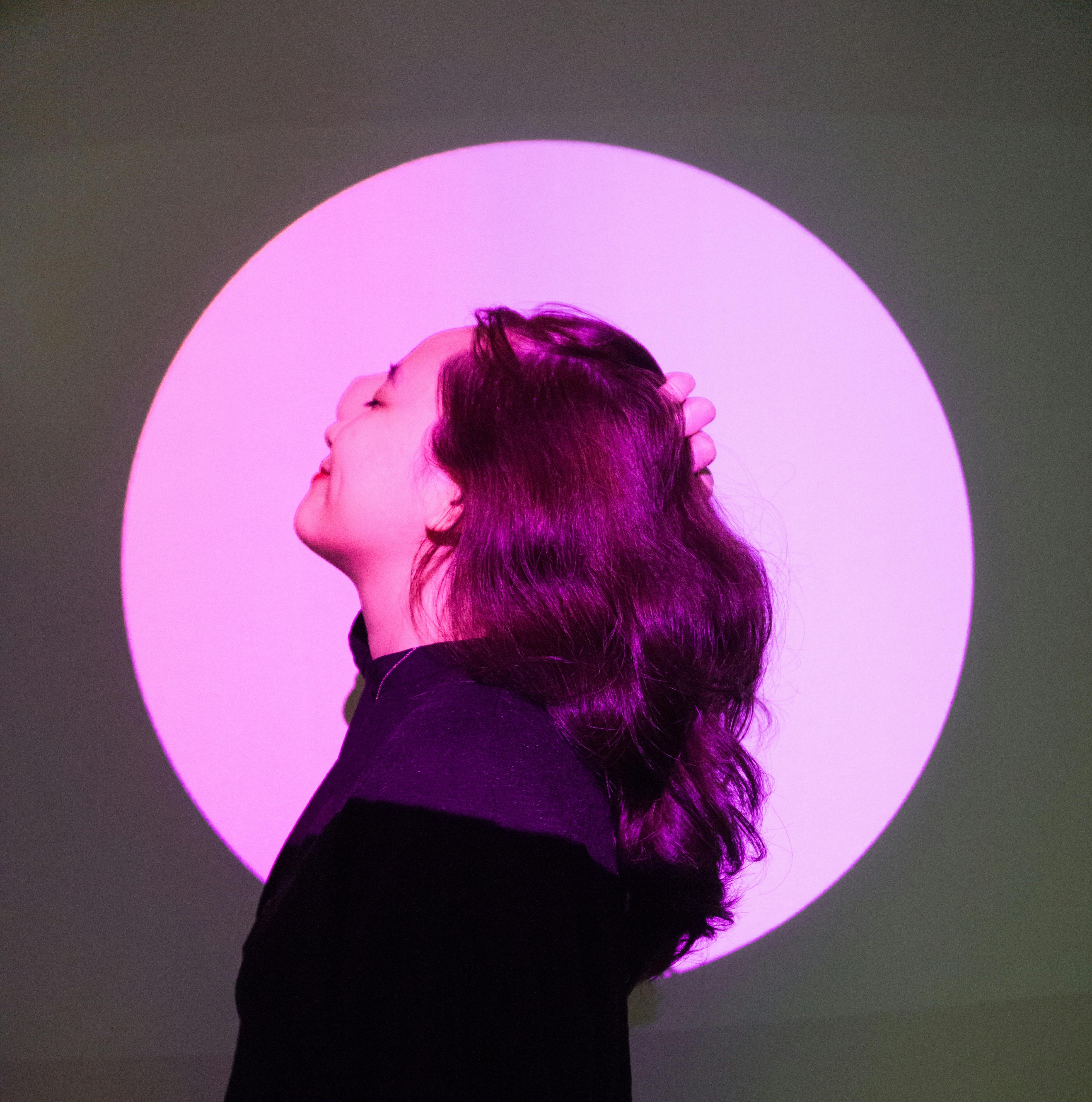 Artistic side view of a woman posing in colorful spotlight, evoking creativity and individuality.