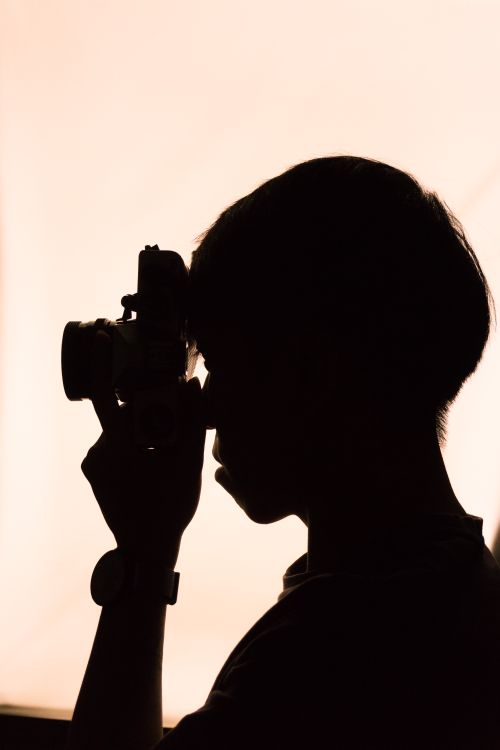 Free Artistic silhouette of a photographer captured holding a camera in striking profile. Stock Photo