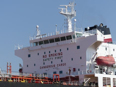 Close-up of a cargo ship's structure displaying safety warnings and emergency equipment.