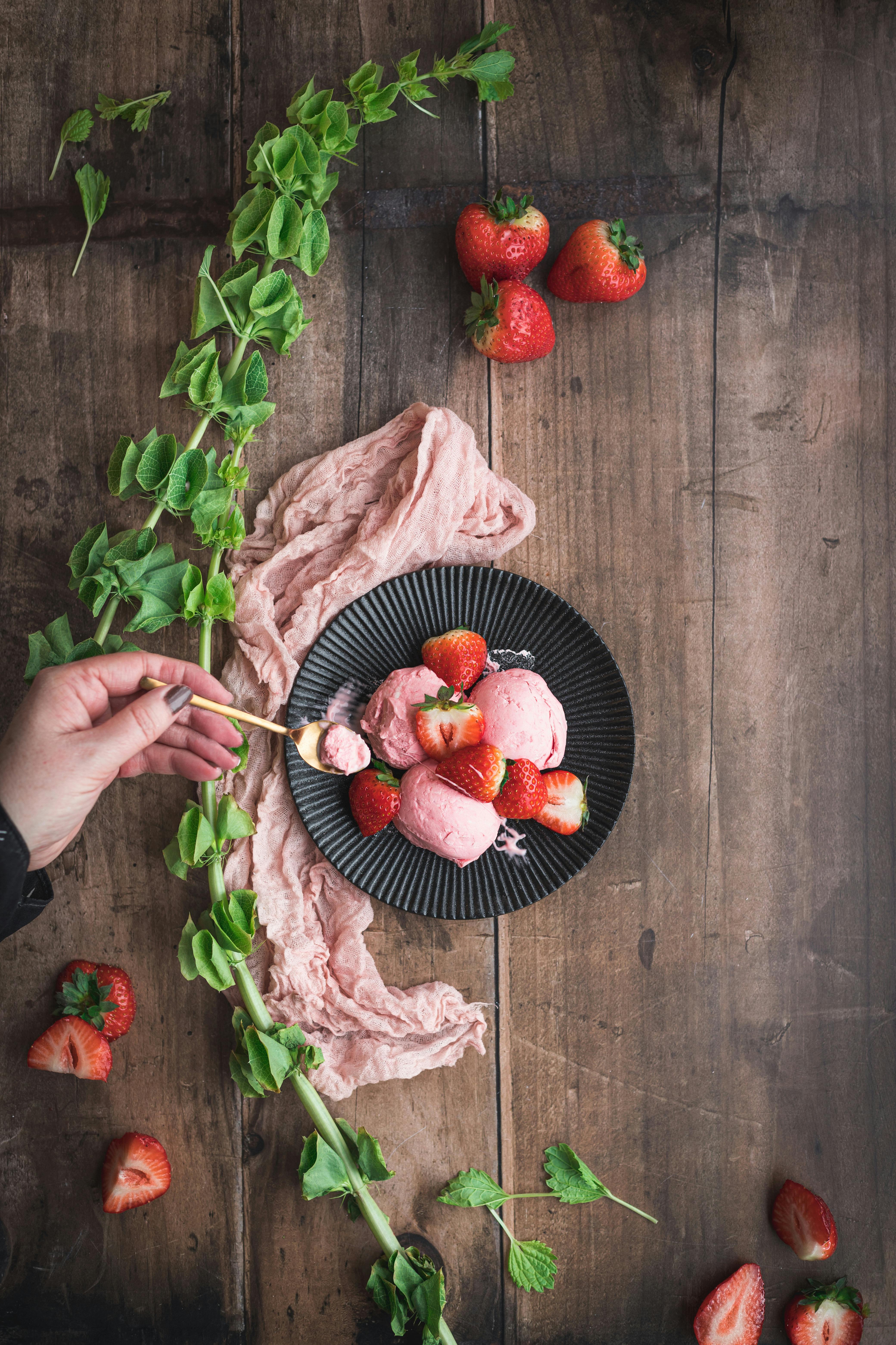 Top-down view of strawberry ice cream with fresh strawberries on a rustic table.