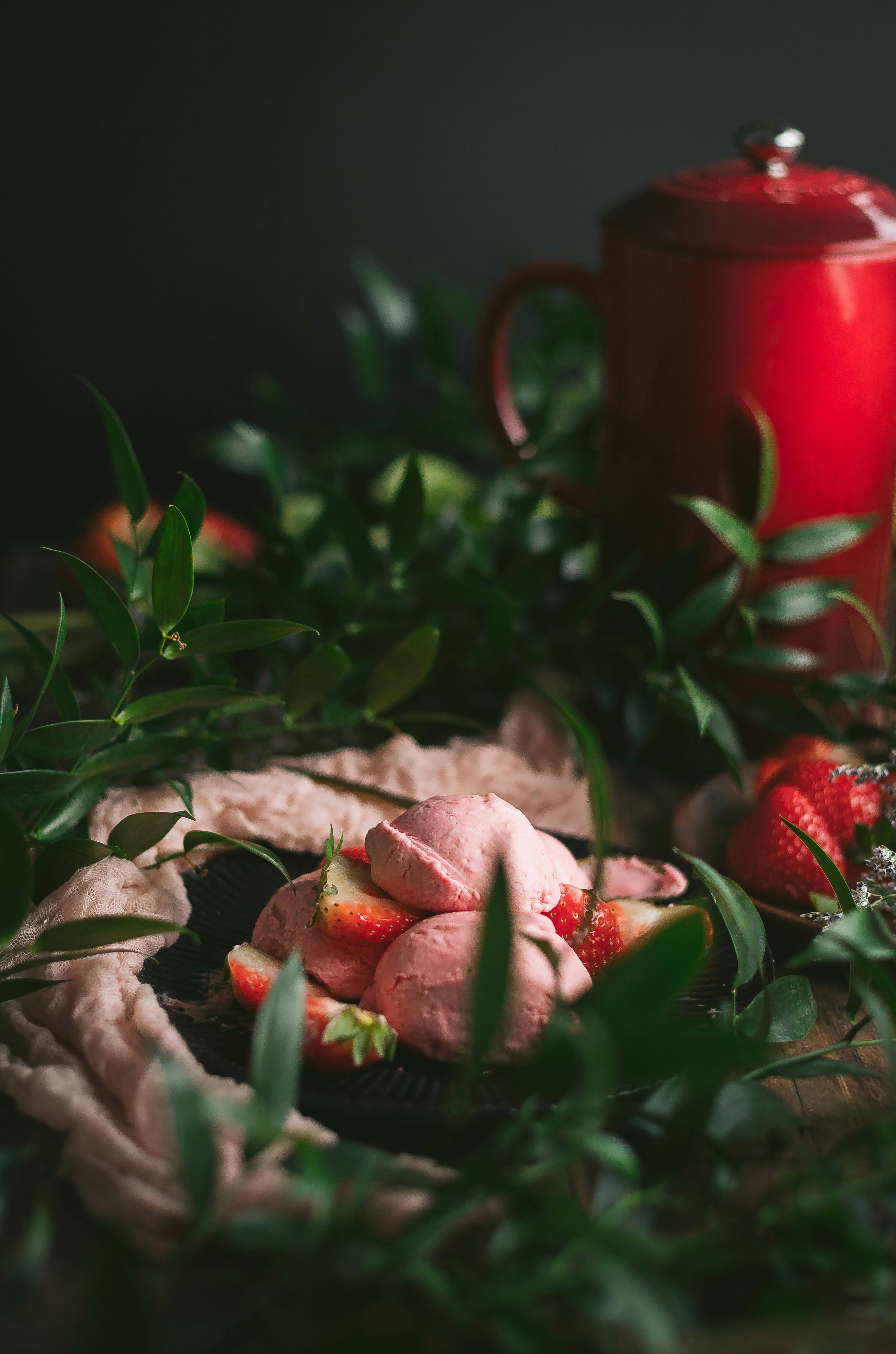 A refined presentation of strawberry ice cream surrounded by fresh green leaves and strawberries, creating a rustic vibe.