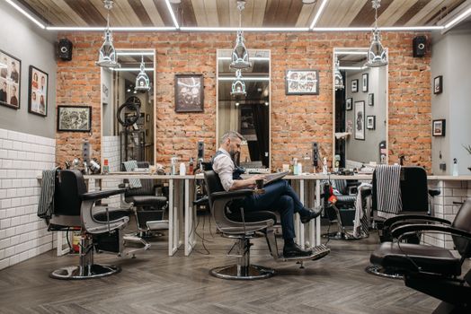 Barber shop interior featuring a man reading a newspaper in a stylish, modern setting.