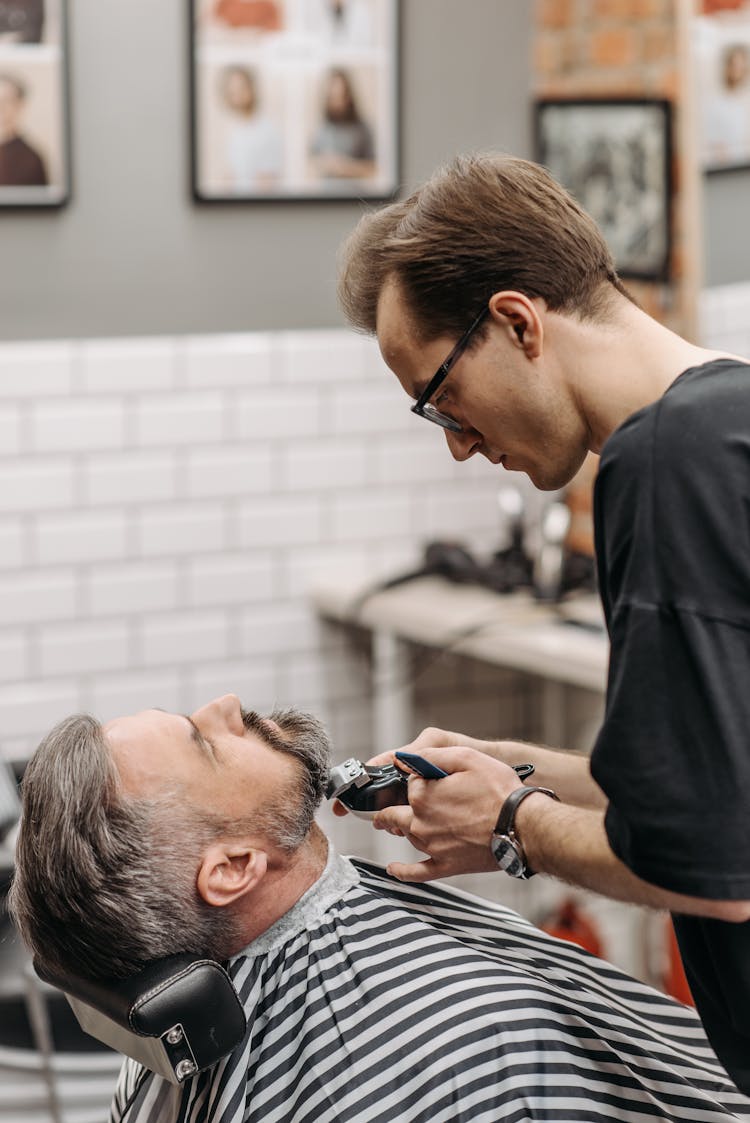 A Barber Cutting A Client's Beard With A Hair Clipper