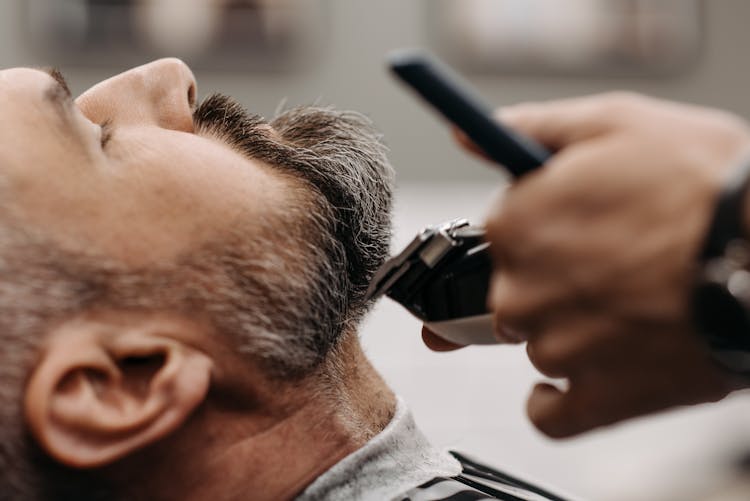 A Barber Cutting A Client's Beard