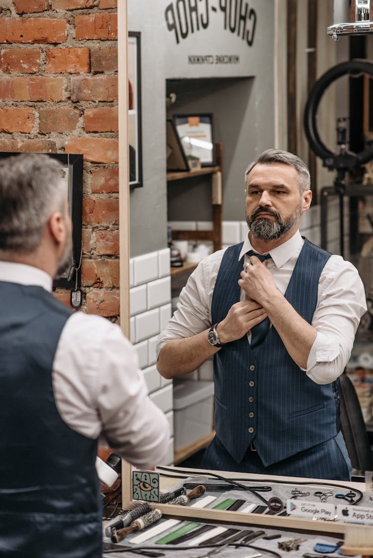 A Barber Fixing His Tie While Looking In The Mirror