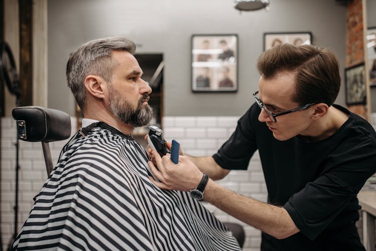 A Barber Cutting A Client's Beard