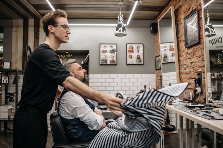 A Barber Placing A Cape On A Client