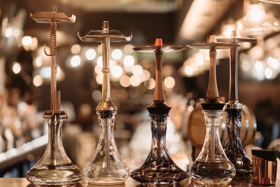 A collection of elegant hookah water pipes set up on a bar counter with warm bokeh lighting