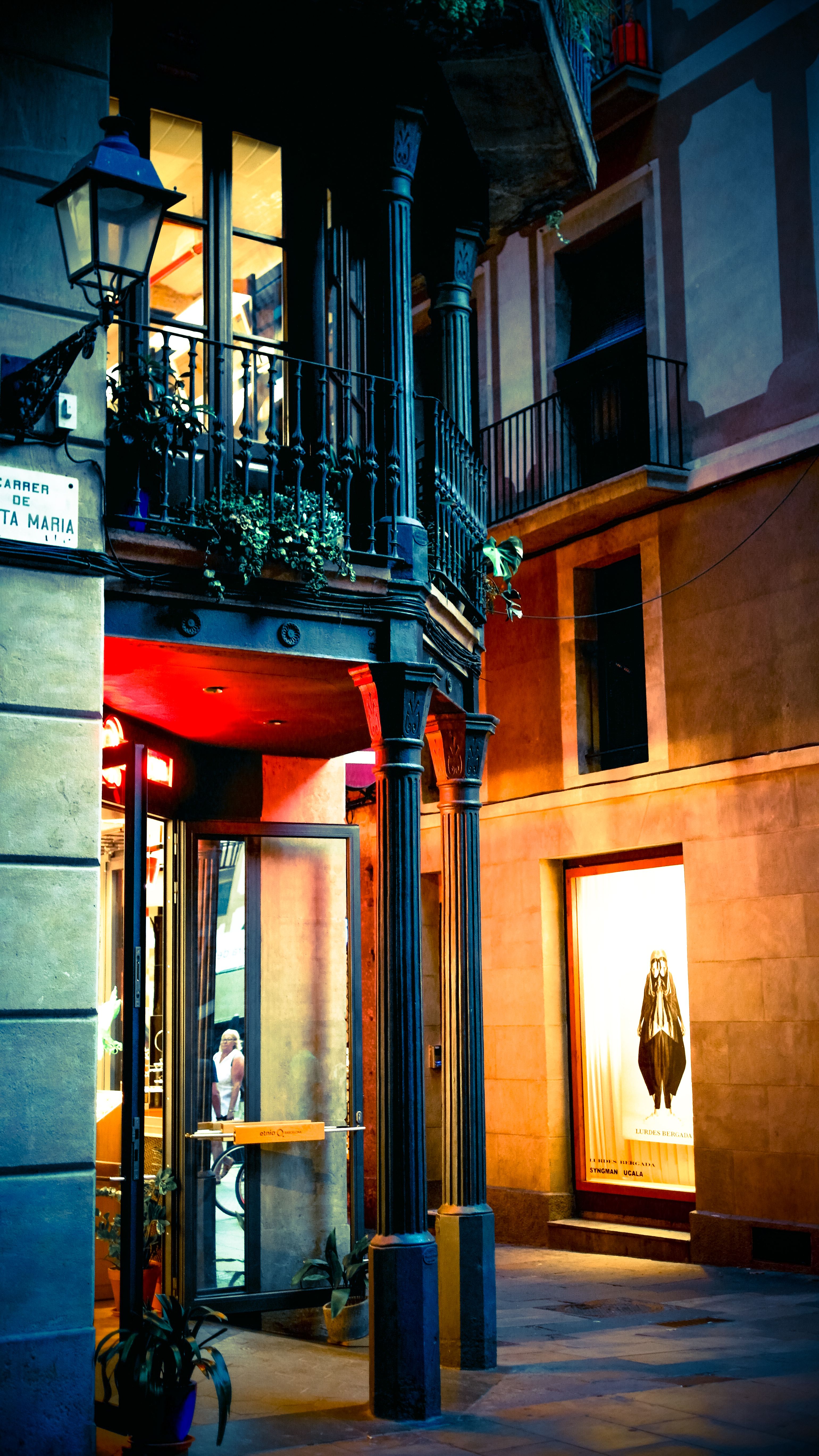 Elegant street corner in Barcelona featuring a stylish balcony and warmly lit boutique.