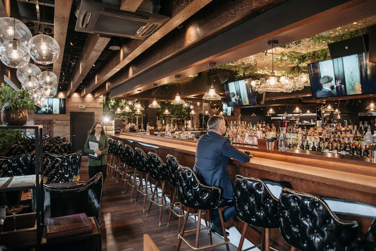 Man In Blue Suit Sitting At The Bar Counter