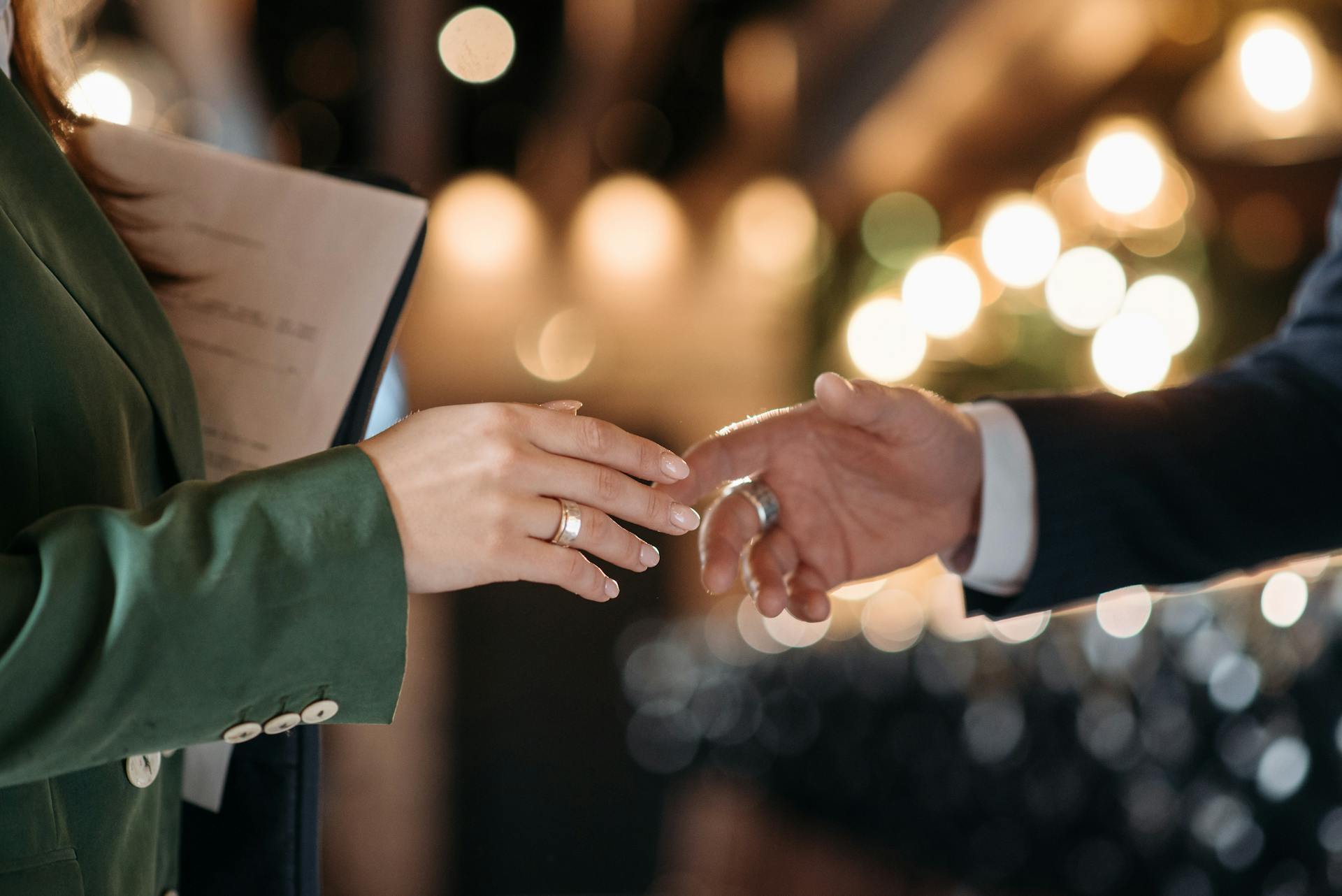 Close-up of business handshake with documents and background lights, symbolizing agreement.